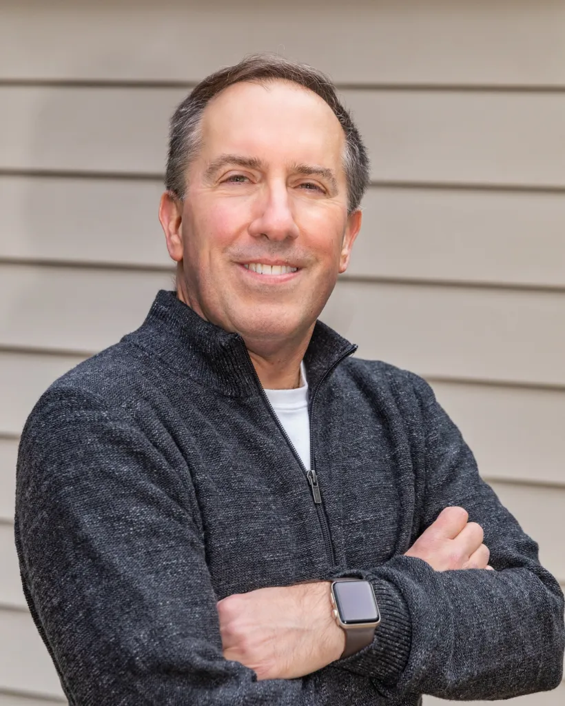 Headshot of Jonathan Koomey smiling with his arms crossed.