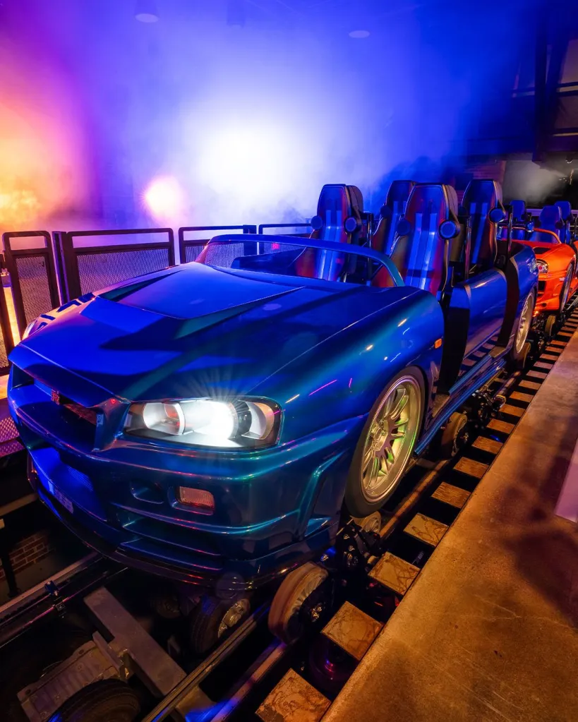 Blue and orange cars of the Fast & Furious: Hollywood Drift roller coaster on a track.