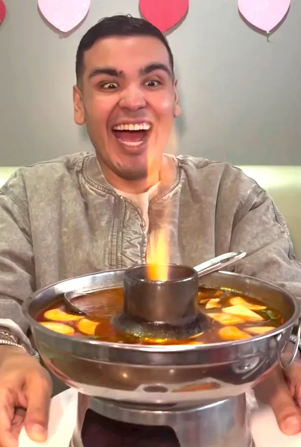 A man joyfully reacting to a flaming hot pot of soup.