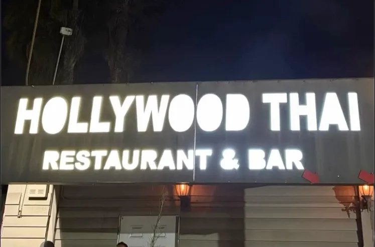 A close-up of the Hollywood Thai Restaurant & Bar sign, brightly illuminated at night.