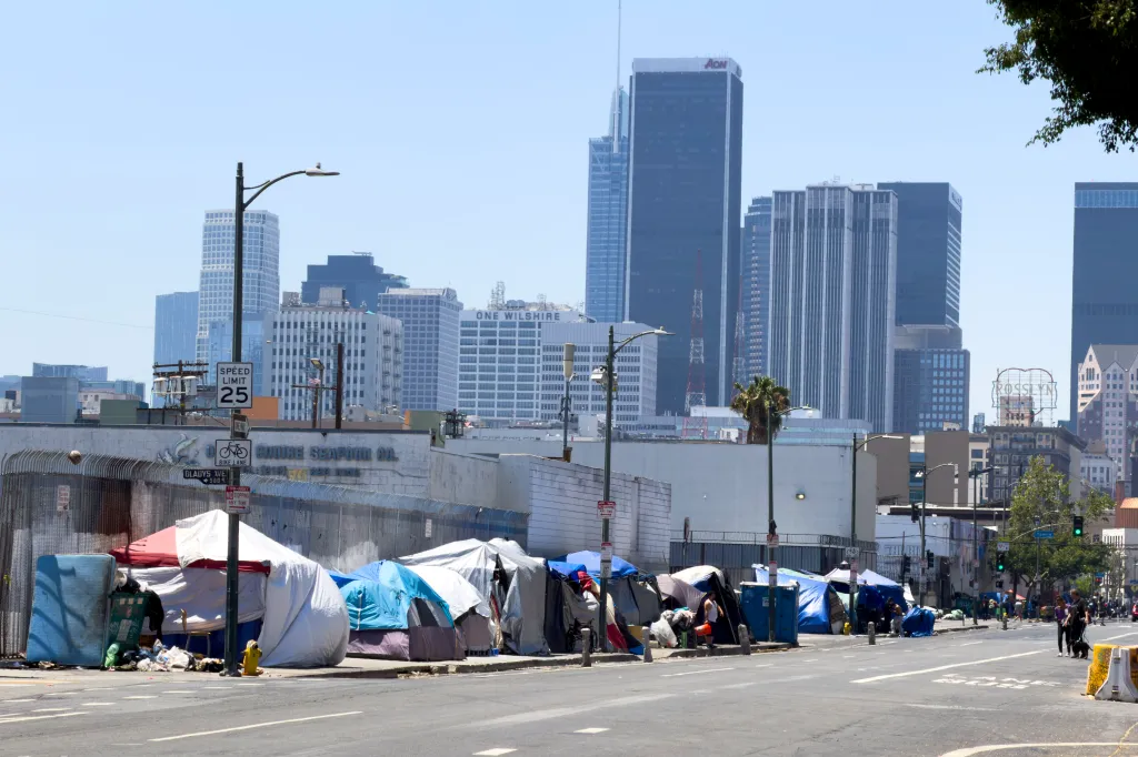 Homeless people living in tents on Skid Row, Los Angeles, with downtown skyscrapers in the background.