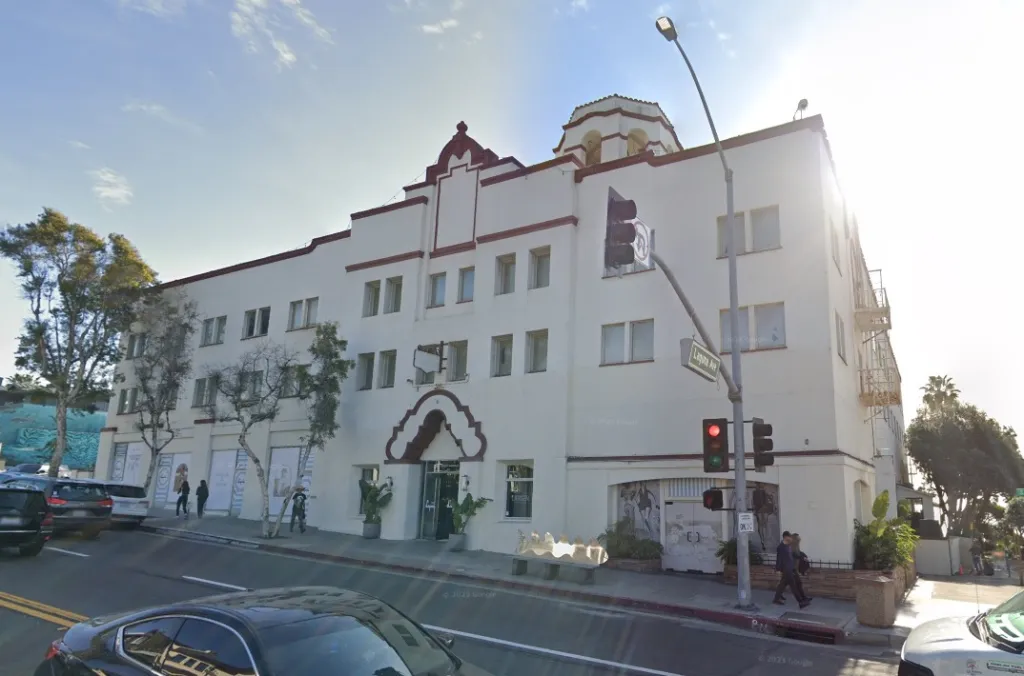 Hotel Laguna at 425 S Coast Hwy, Laguna Beach, CA, a white multi-story building with dark red trim and a dome, under a bright sky.