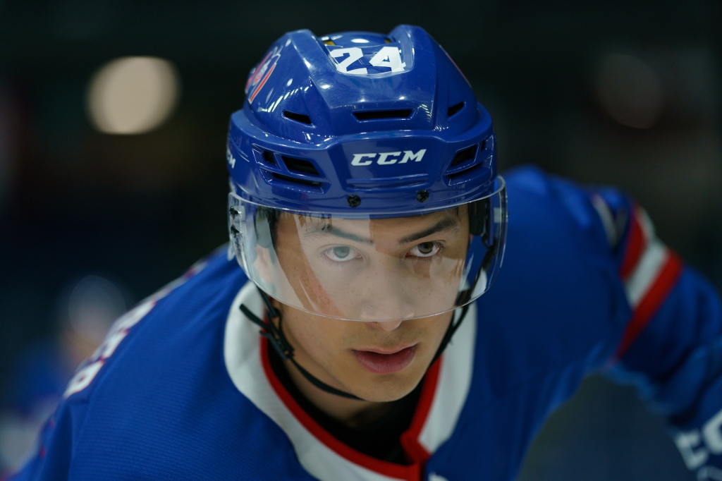 Hudson Williams as Shane Hollander in a blue hockey helmet and jersey.