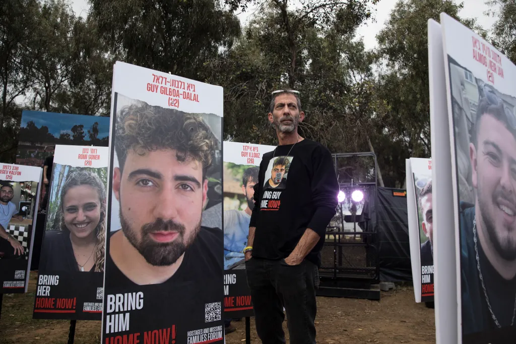 Ilan Gilboa Dalal stands next to a poster of his son, Guy Gilboa Dalal, who is being held hostage by Hamas, at the Nova music festival site.