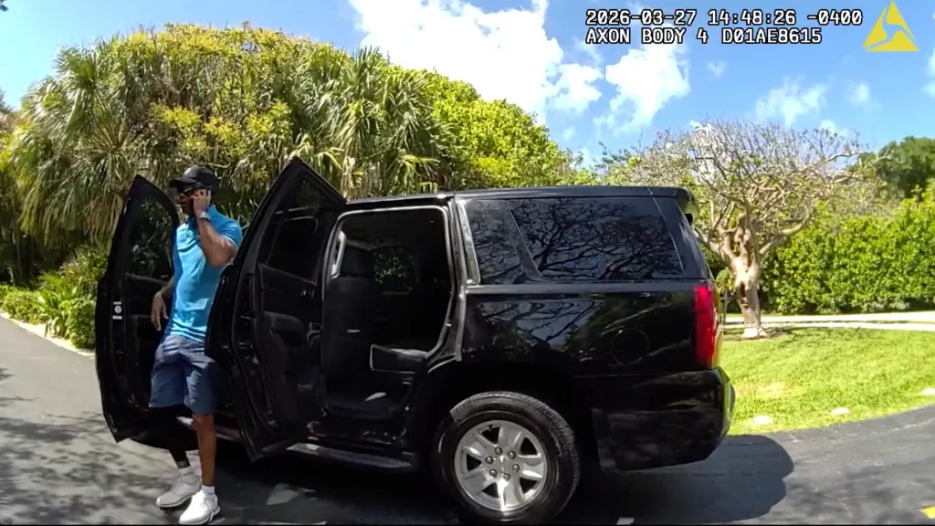 Golfer Tiger Woods exiting an unmarked police vehicle while speaking on his cellphone after a car crash.