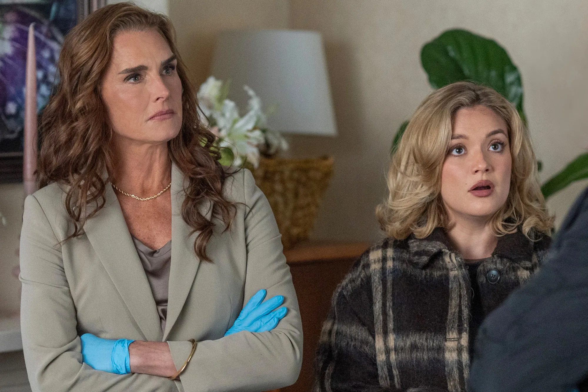 Brooke Shields wearing blue gloves and a young blonde woman looking surprised.