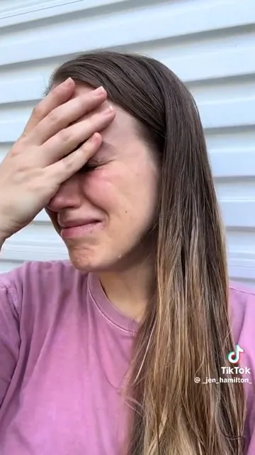 Influencer Jen Hamilton crying and covering her face with her hand.