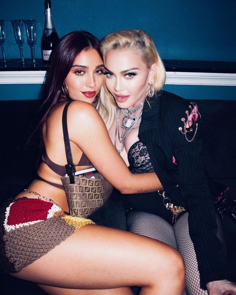 Madonna embracing a woman with long dark hair, both looking at the camera.