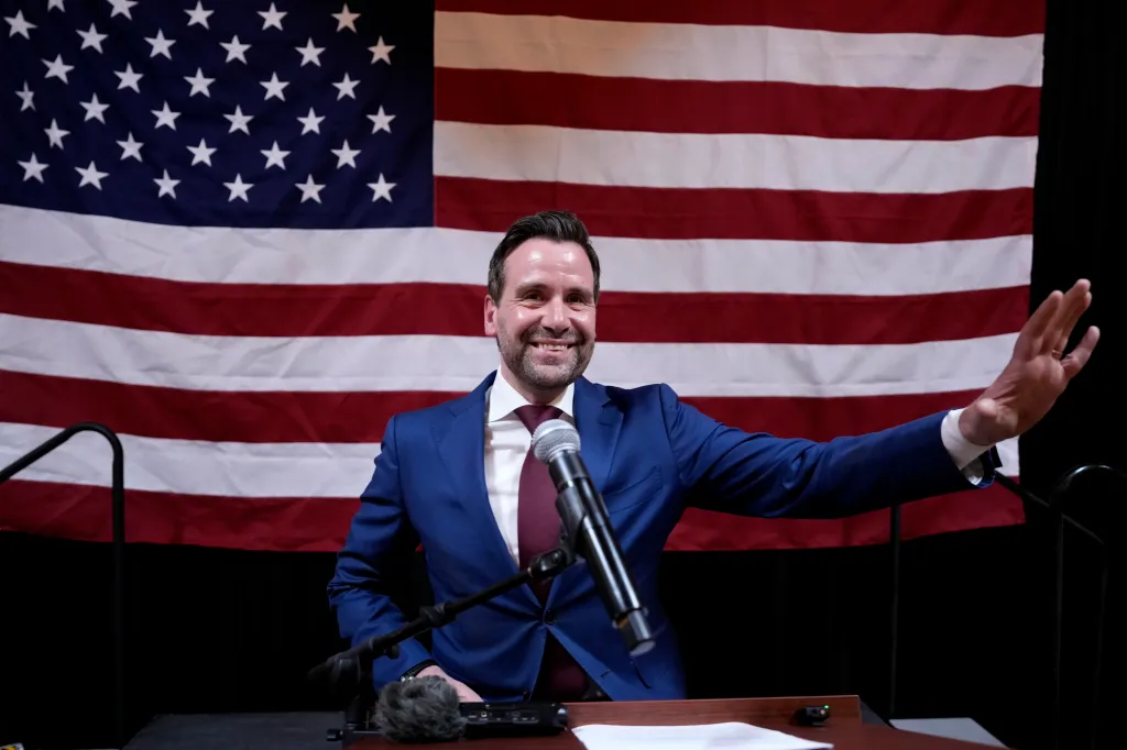 Josh Turek, Iowa Democratic U.S. Senate candidate, speaking at a rally with an American flag behind him.