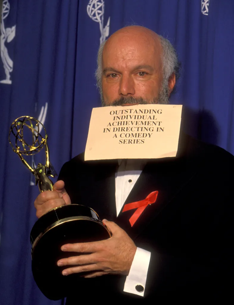 James Burrows holding an Emmy award and a sign reading 