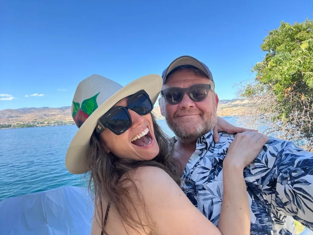 Heather McComb and husband Scott Michael Campbell pose for a selfie by a lake.