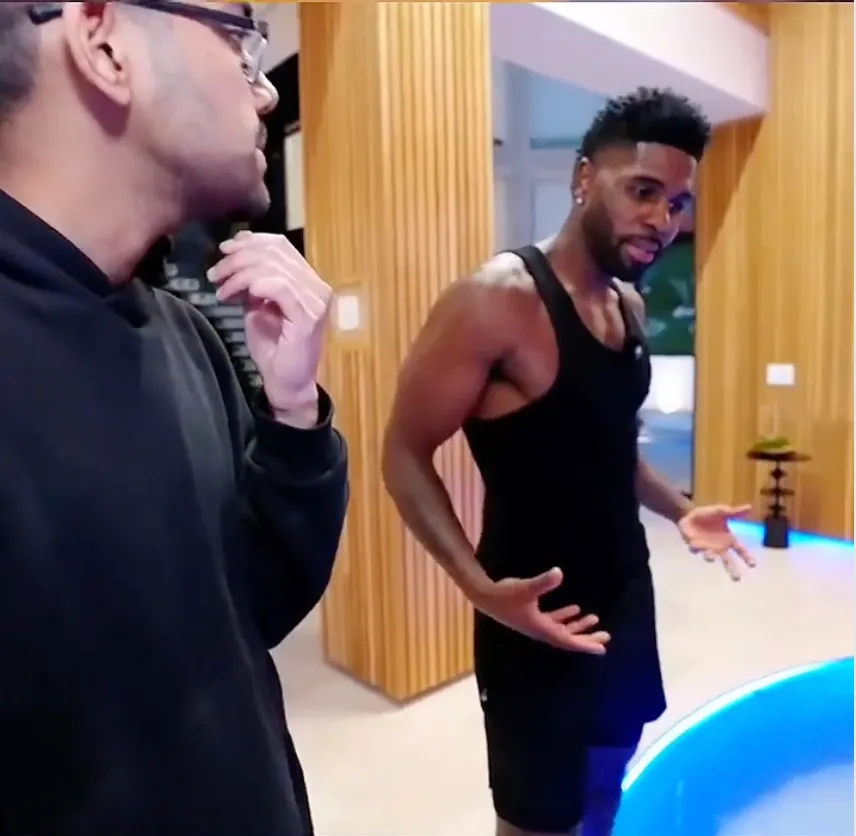 Jason Derulo standing next to a shark tank.