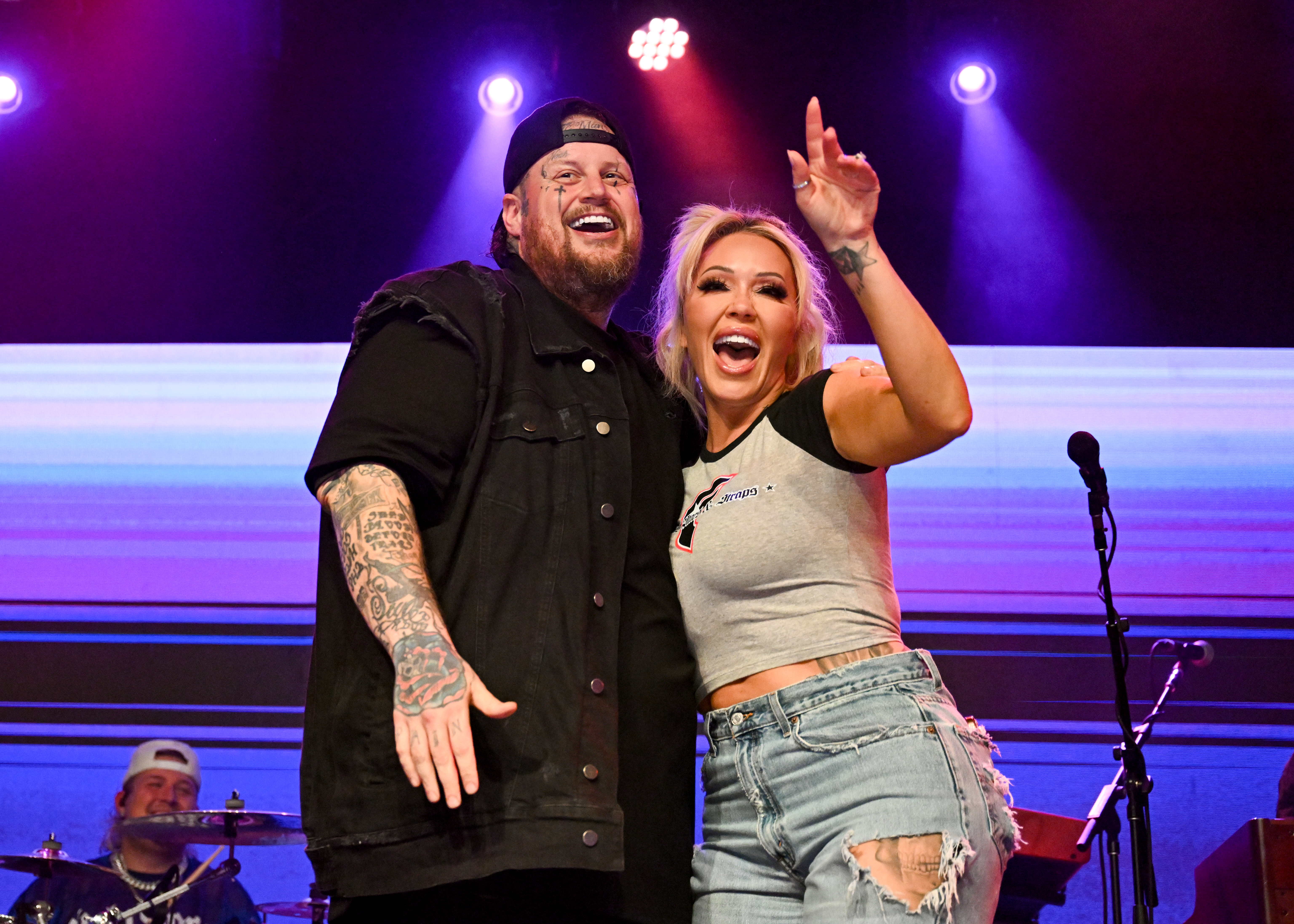 Jelly Roll and Bunnie Xo smiling on stage at a concert.