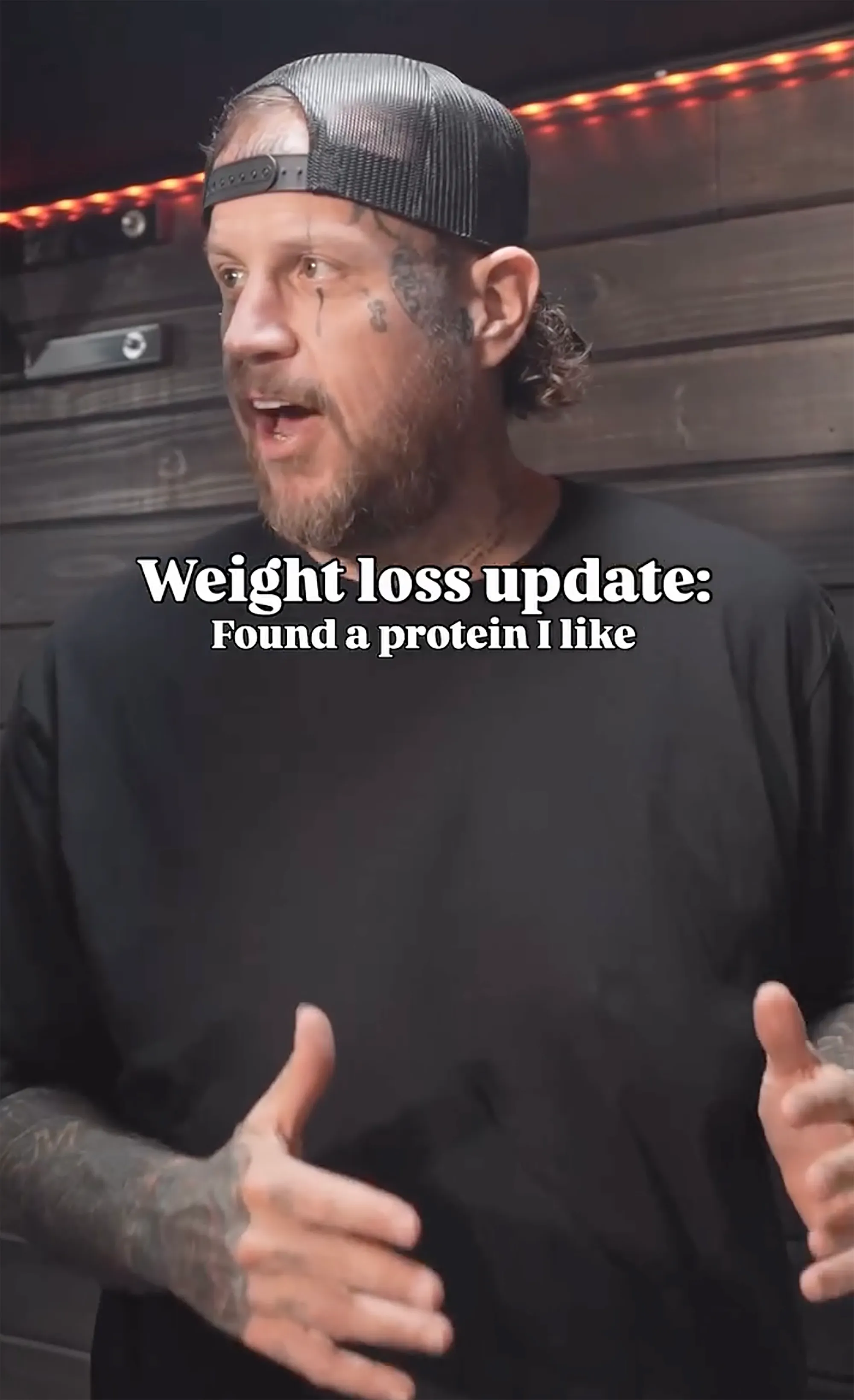Jelly Roll speaks to the camera in a black t-shirt and trucker hat.