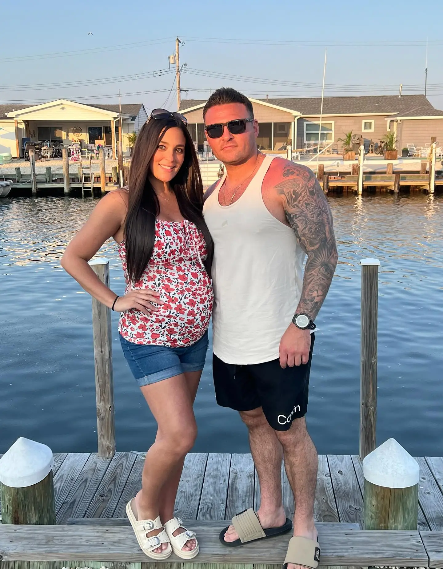 Sammi Giancola with her fiancé Justin May posing on a dock by the water.