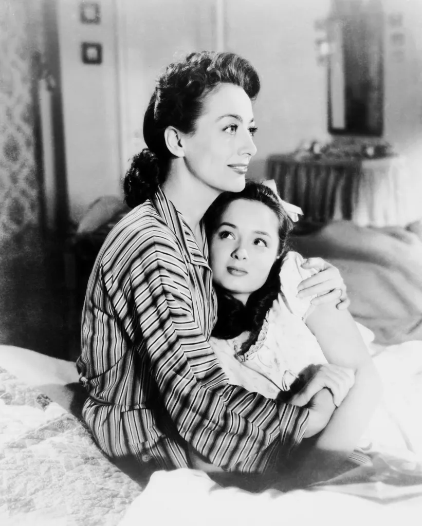 Joan Crawford embracing Ann Blyth on a bed.