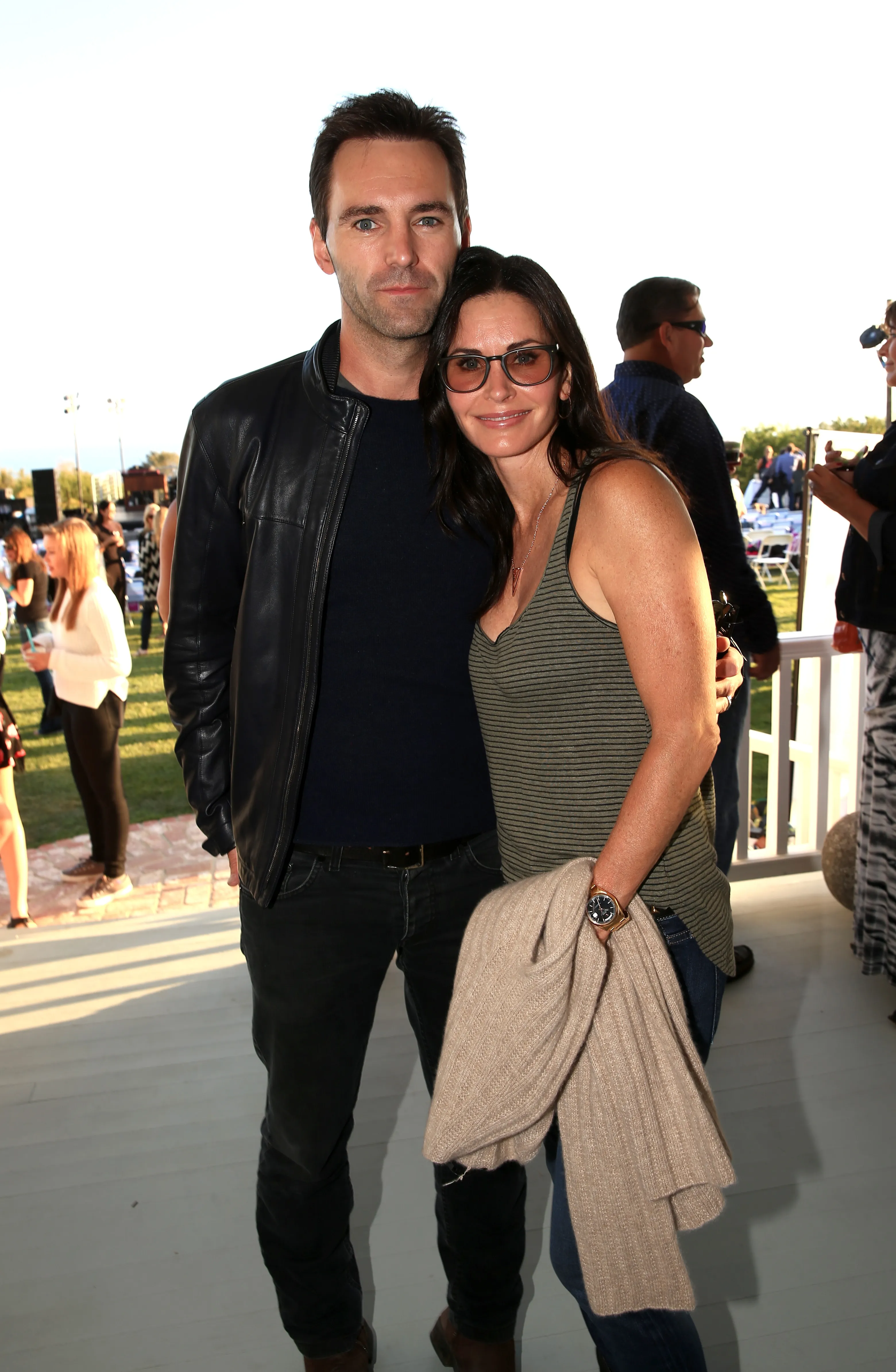 Johnny McDaid and Courteney Cox pose for a photo with Cox's arm around McDaid's waist.