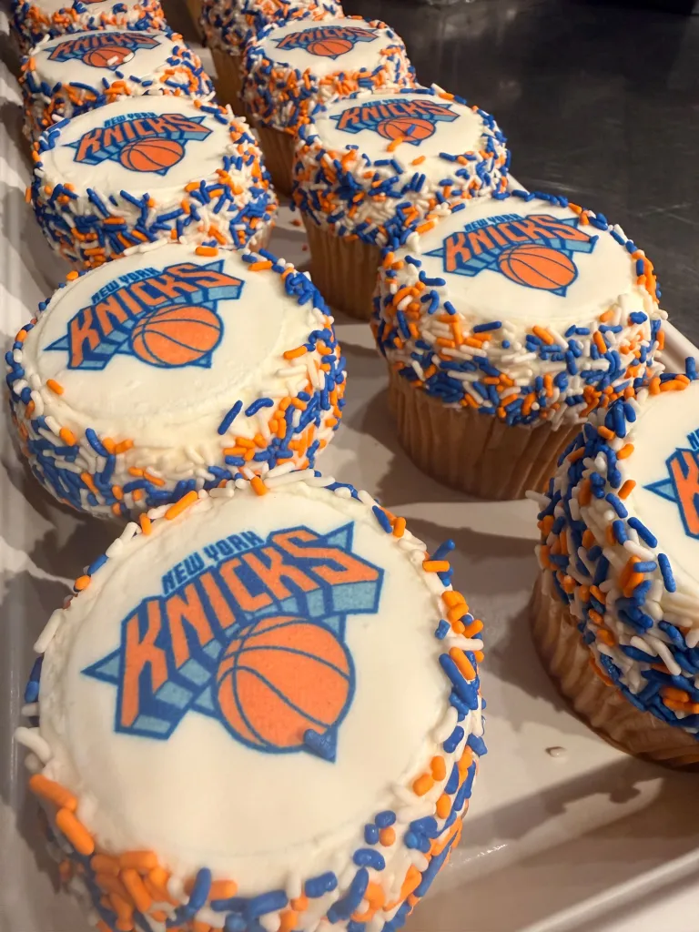 Cupcakes from Junior's Restaurant and Bakery decorated with New York Knicks logos and blue, white, and orange sprinkles.
