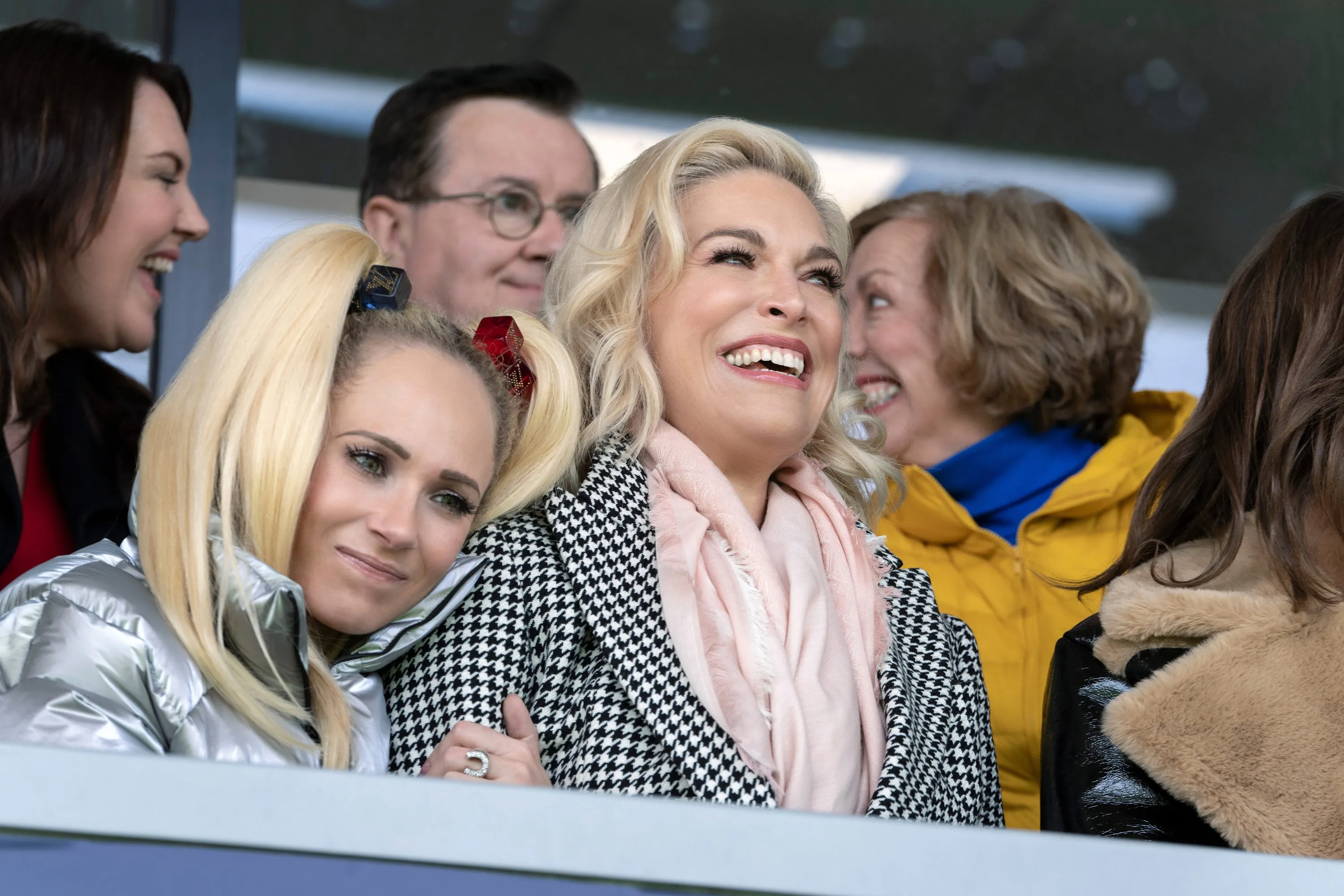Juno Temple and Hannah Waddingham are shown in a crowd, both with excited expressions.