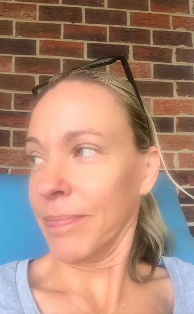 Kate Gosselin in a light blue shirt looking to the side with a brick wall behind her.