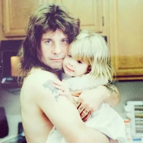 Ozzy Osbourne holding his young daughter, Kelly.