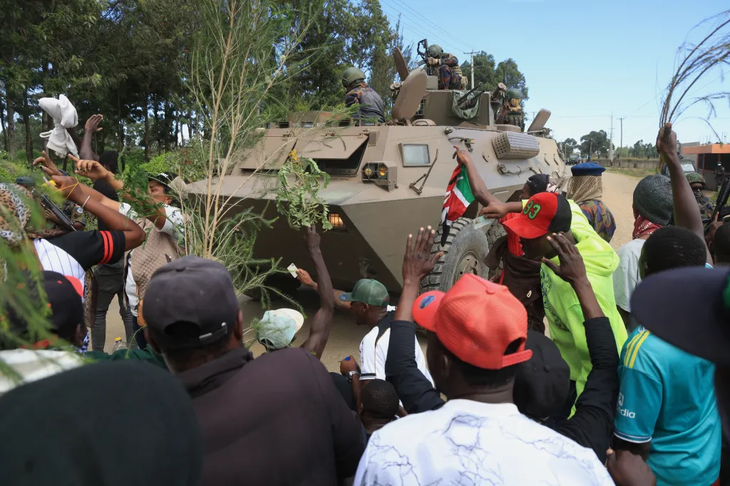 Protesters demonstrating against a proposed Ebola quarantine center surround a tank carrying Kenyan soldiers.