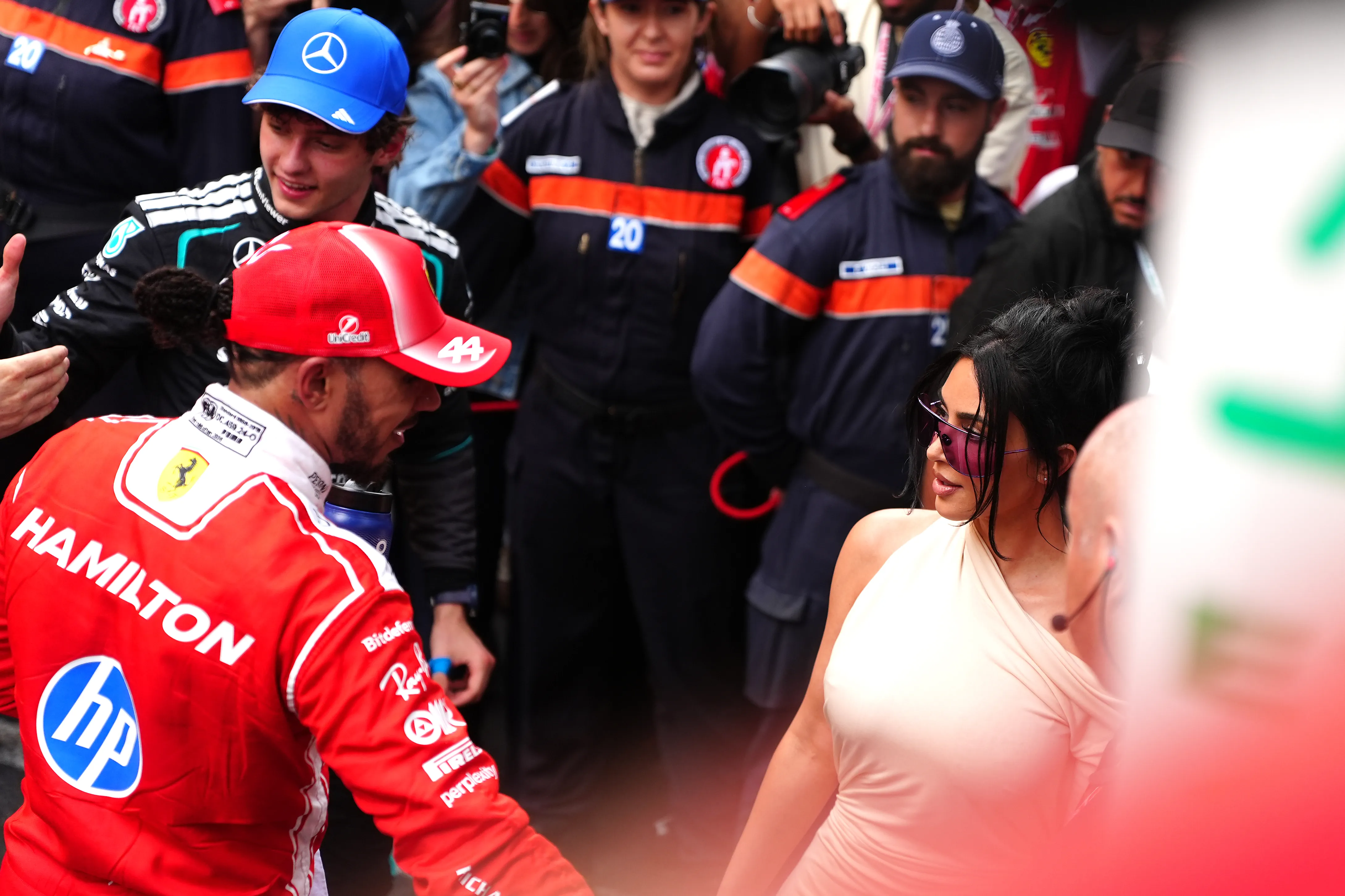 Lewis Hamilton, wearing a red Ferrari racing suit and red cap, with Kim Kardashian, wearing a cream dress and pink sunglasses, at the Monaco Grand Prix.