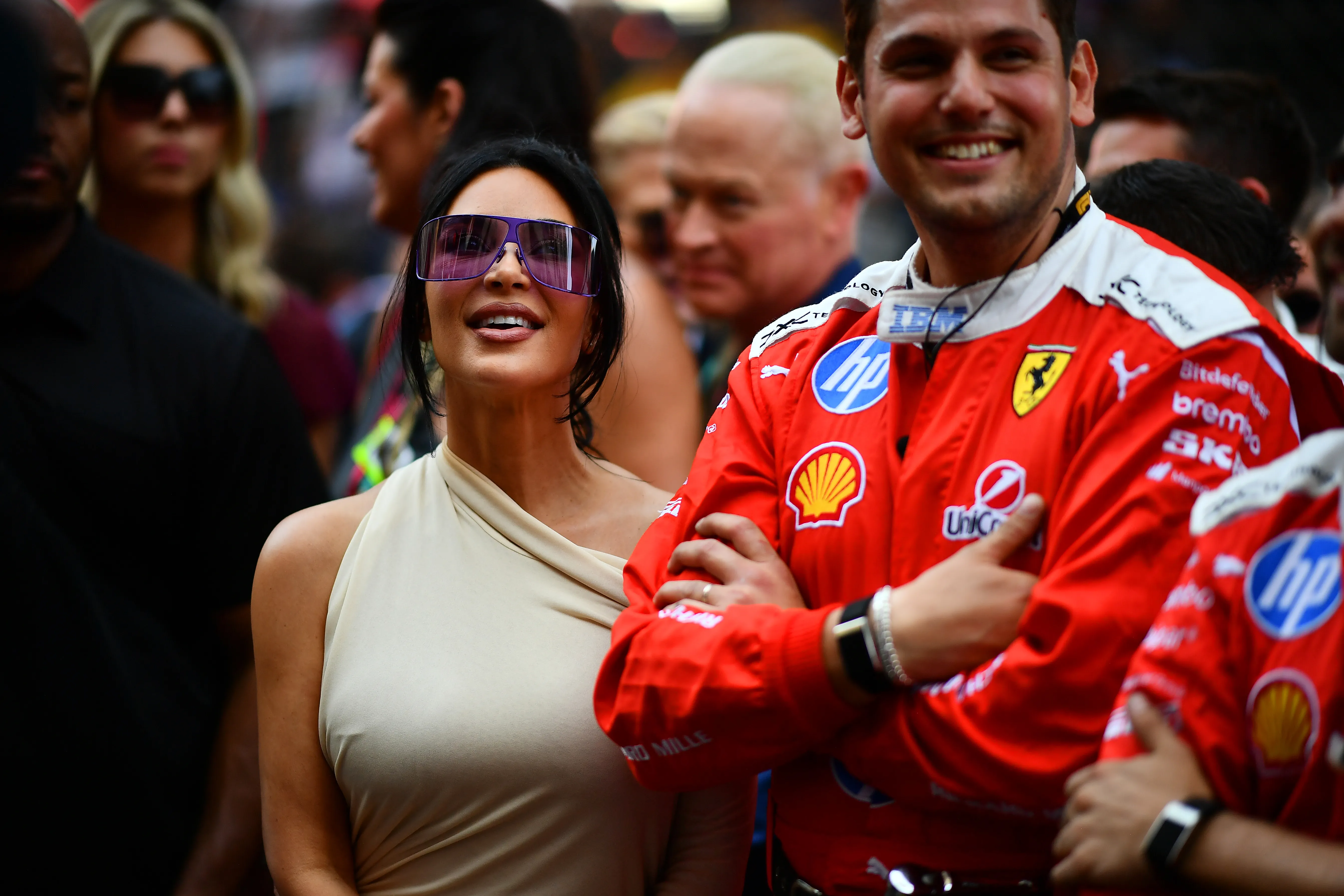 Kim Kardashian with purple sunglasses next to a Ferrari team member in red uniform at the F1 Grand Prix of Monaco.