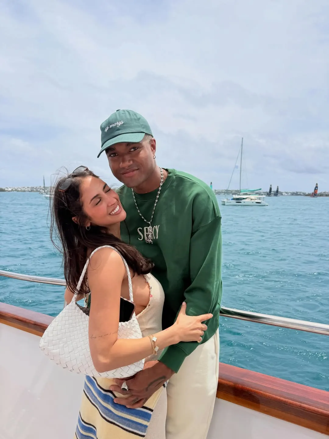 KJ Dillard and Dara Levitan embracing on a boat with the ocean and other boats in the background.