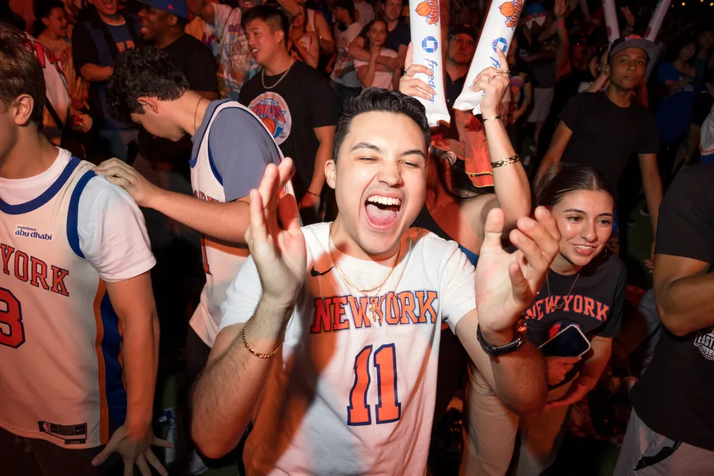 Knicks fans at SummerStage party in Central Park, cheering and clapping.
