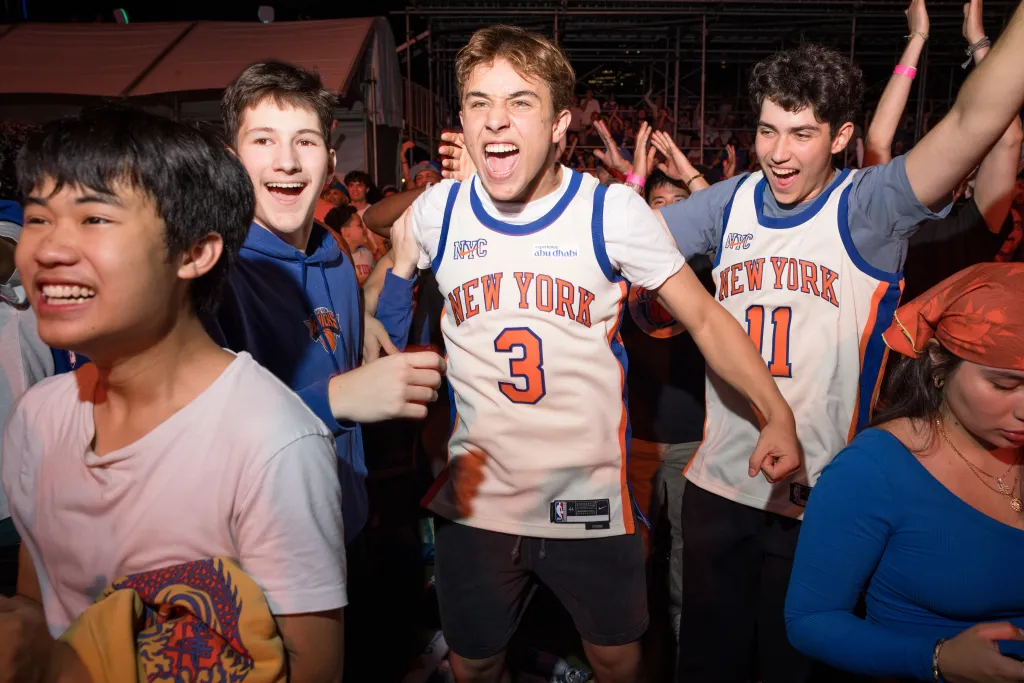 Enthusiastic Knicks fans at a SummerStage party in Central Park, wearing jerseys.