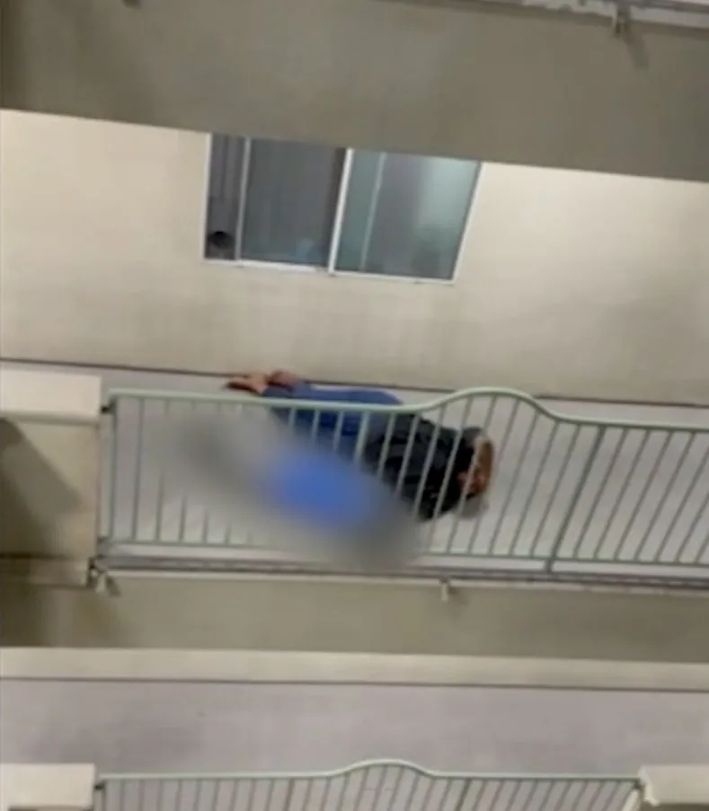 A man slumped over a balcony railing.