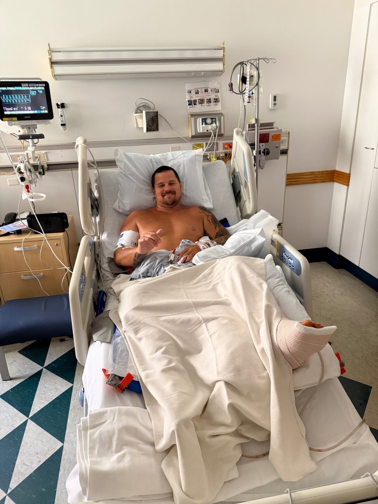 Koa Smith in a hospital bed with his injured foot wrapped.