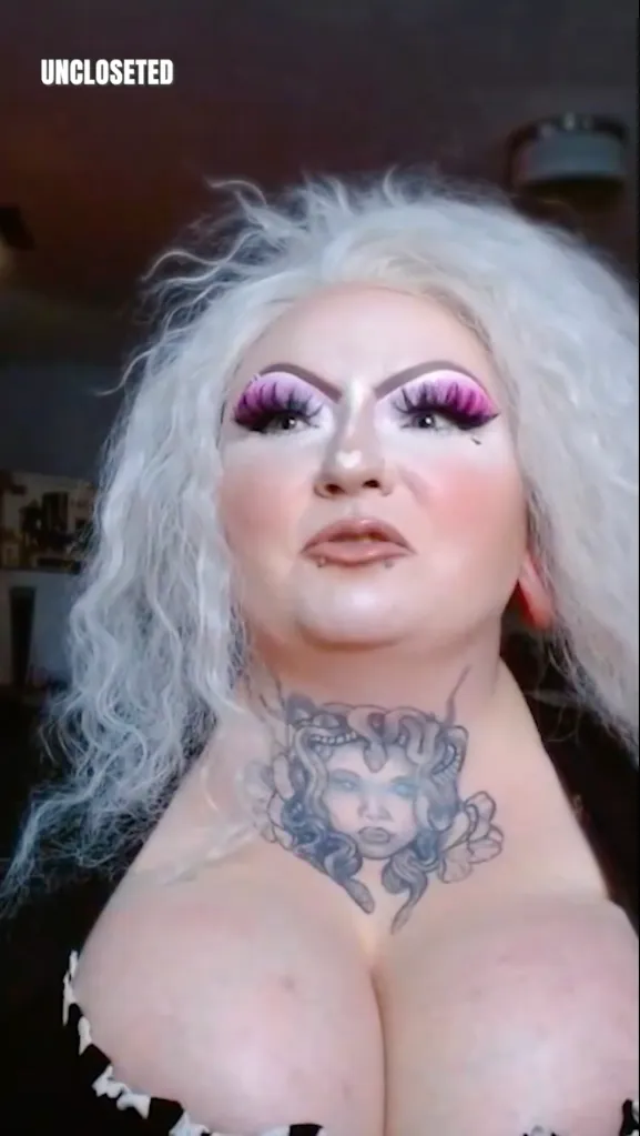 A person in drag makeup with a Medusa tattoo on their chest.