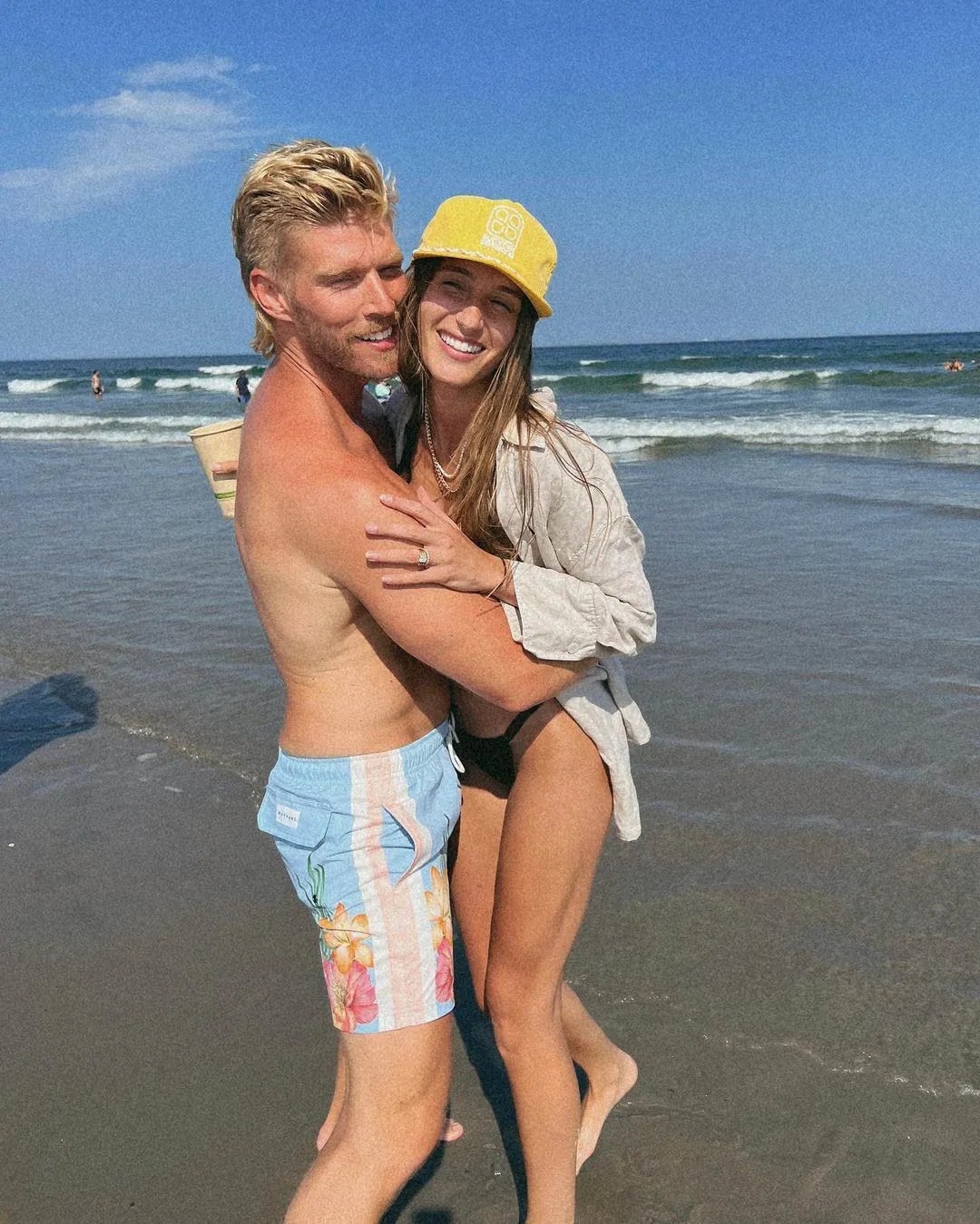 Kyle Cooke and Amanda Batula smiling and embracing on a beach.