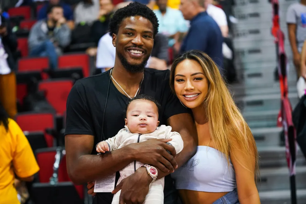 Malik Beasley, Montana Yao, and their son Makai Beasley pose courtside at an NBA Summer League game.