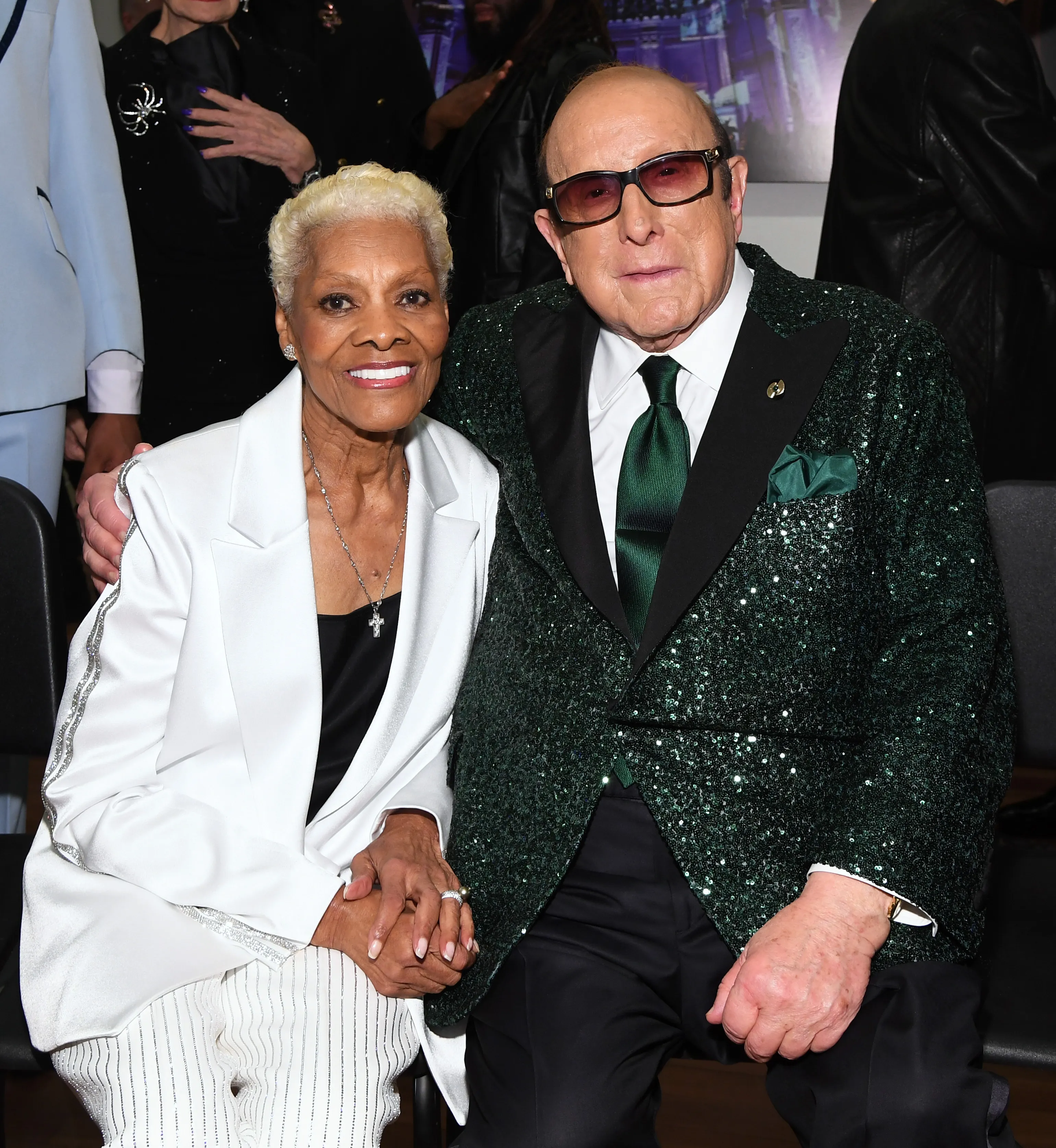 Dionne Warwick and Clive Davis holding hands at an event.