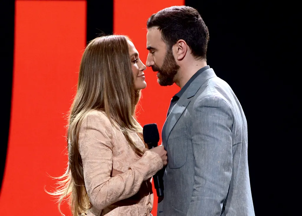 Jennifer Lopez and Brett Goldstein speak onstage during the 2026 Netflix Upfront.