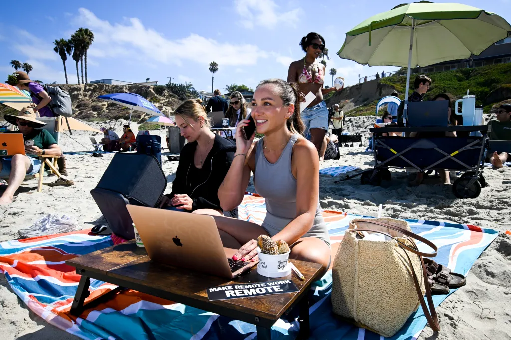 Lacey Mallow works on her laptop on the beach in Pacific Beach as she takes part in a Remote Work event in San Diego.
