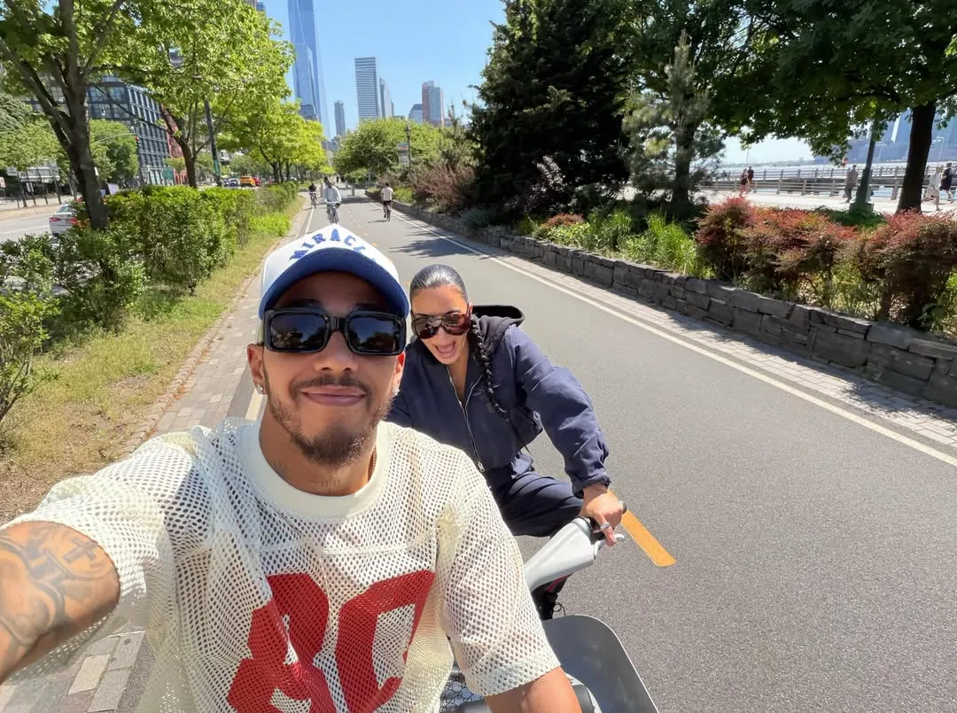 Lewis Hamilton taking a selfie while biking with Kim Kardashian on a sunny day.