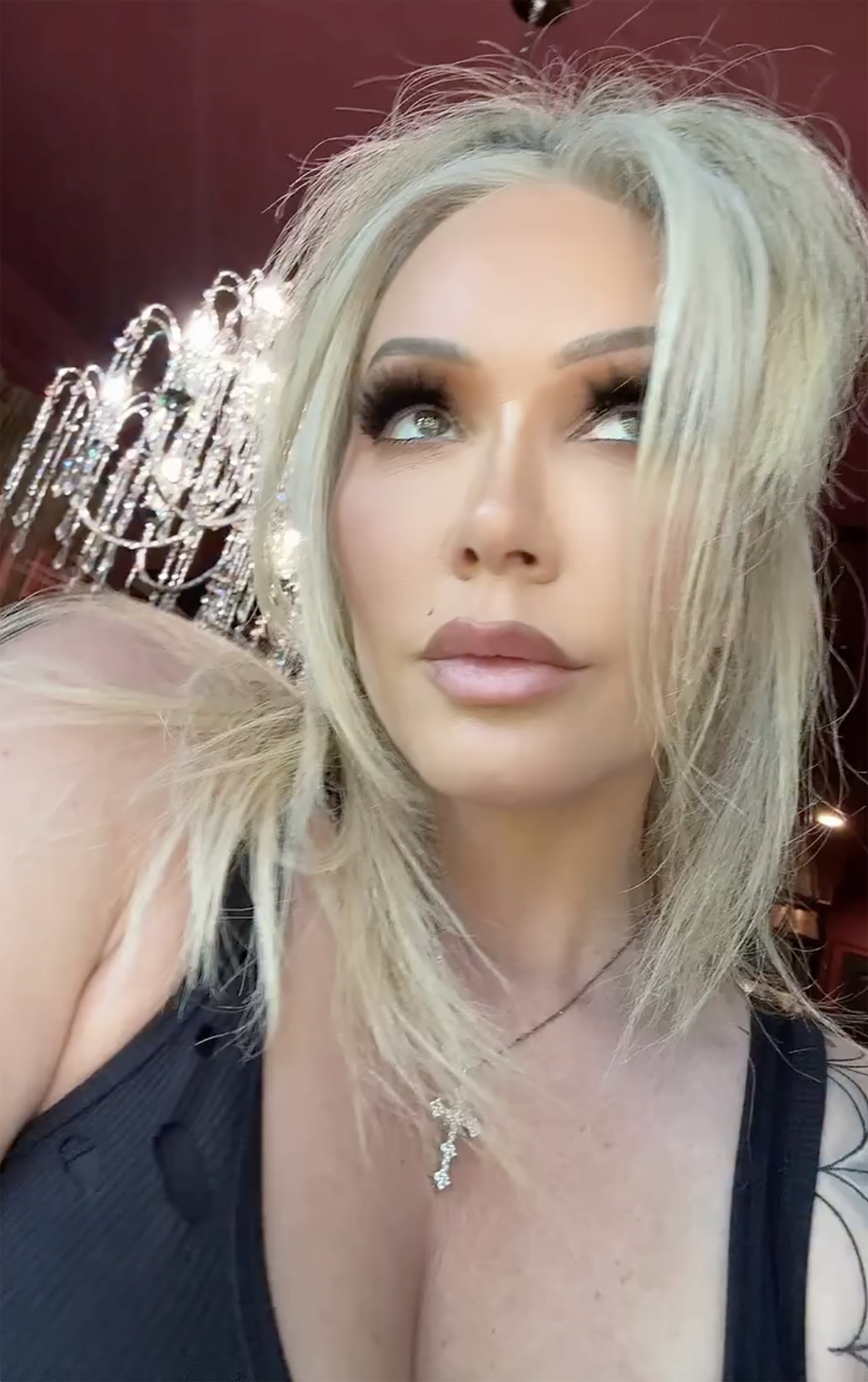 Bunnie XO wearing a black top and a cross necklace.