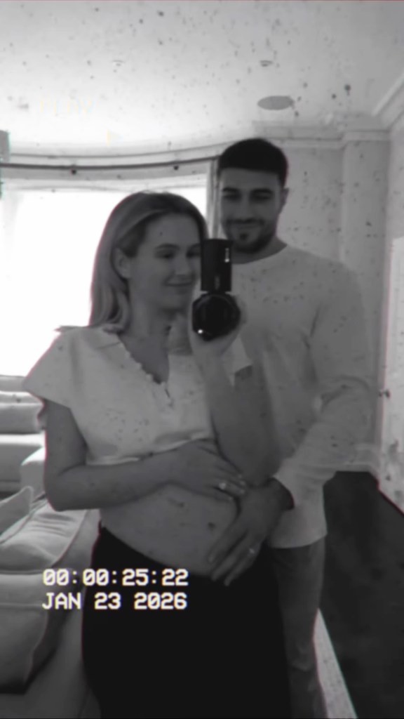Molly-Mae Hague taking a mirror selfie with Tommy Fury, with her hands cradling her pregnant belly and his hand resting on hers.