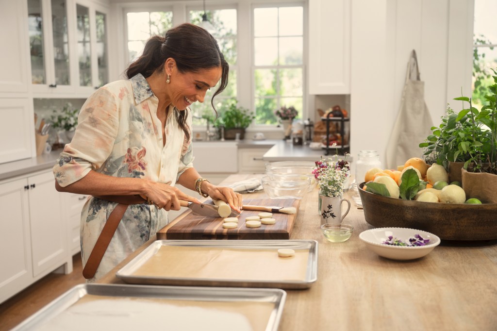 Meghan Markle slicing cookie dough from a roll.