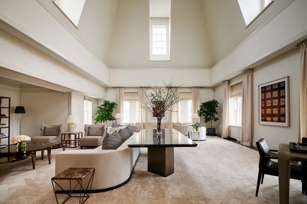 A luxurious and spacious living room with high ceilings, several seating areas, and a dining table.