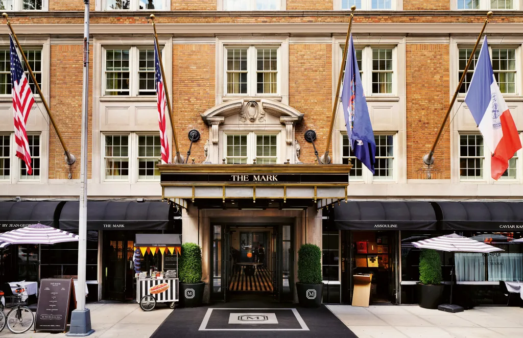 The Mark Hotel in New York City, a brick building with white trim, is seen from the street, with an awning reading 