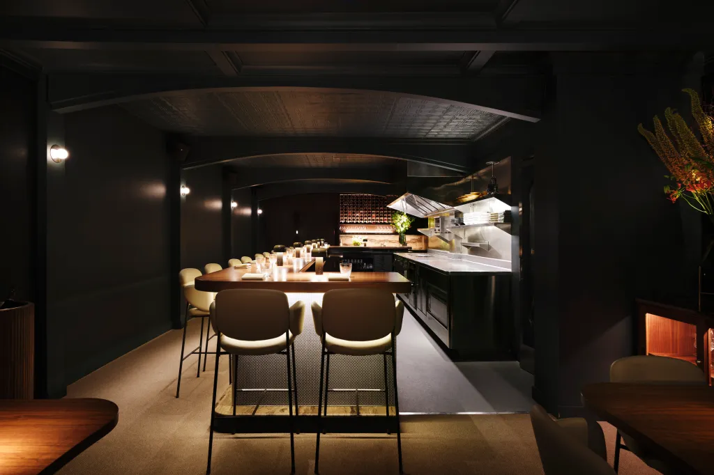 An upscale restaurant dining counter with chairs and an open kitchen.