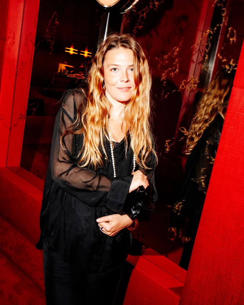 Maggie Rogers in a black sheer top and pearl necklace.