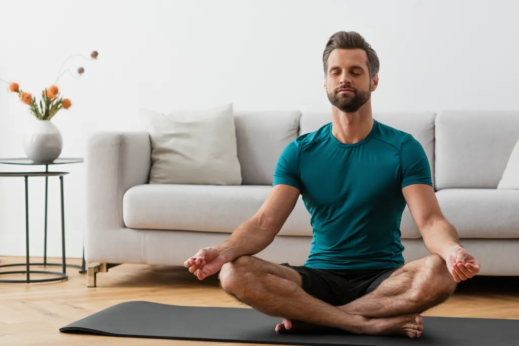 A man meditating in lotus pose on a yoga mat.