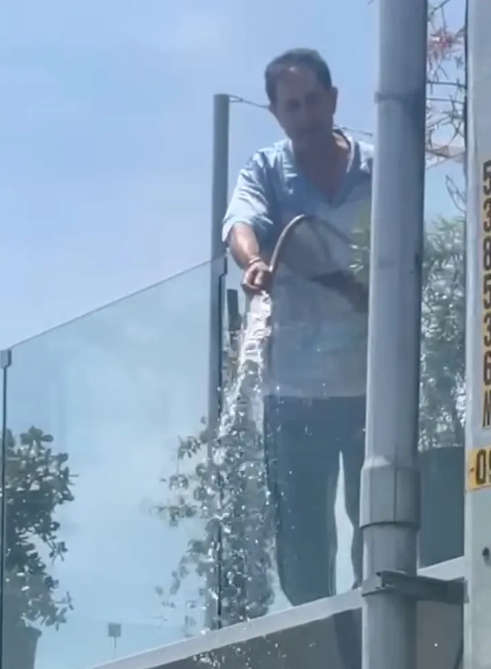 A man pouring water from a balcony.