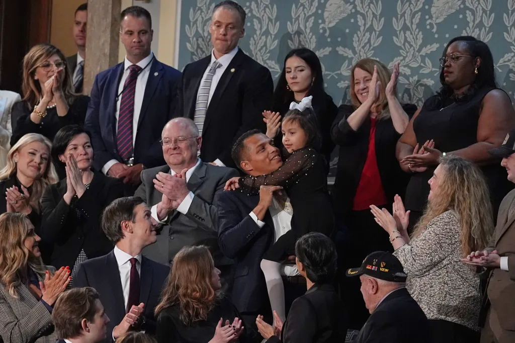 Marcus Coleman holding his daughter Dalilah Coleman while others around them are clapping.